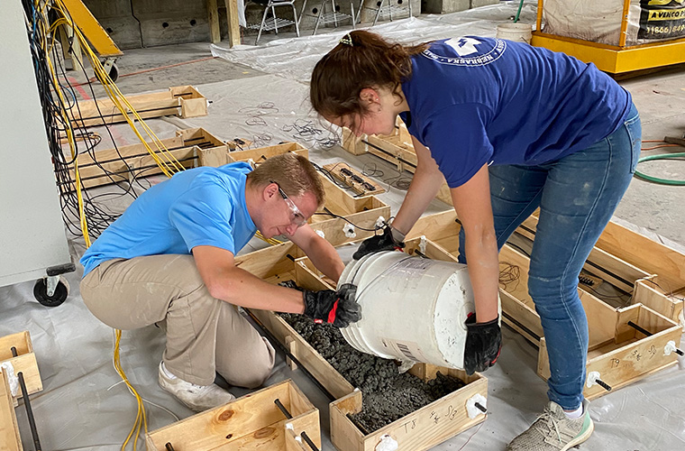 Two UL Lafayette civil engineering students pouring concrete.